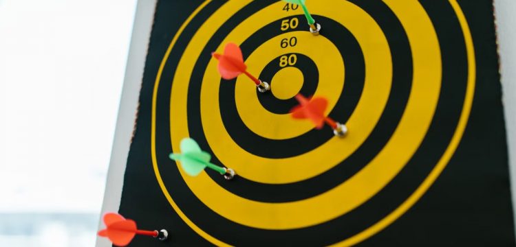 Vibrant darts stuck in a yellow and black dartboard representing precision and strategy.