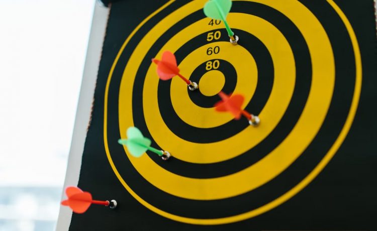 Vibrant darts stuck in a yellow and black dartboard representing precision and strategy.